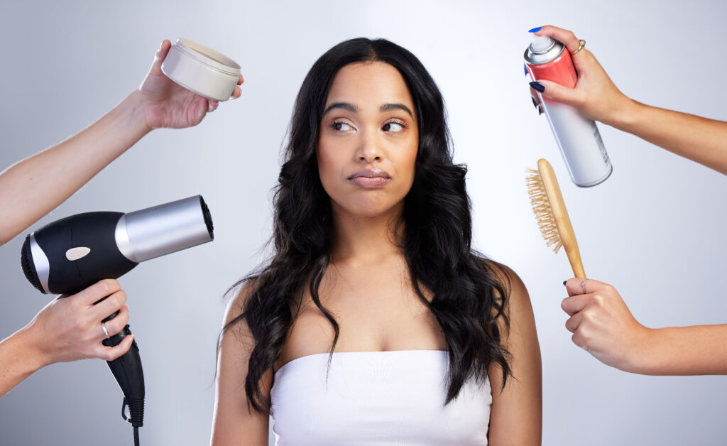 Woman overwhelmed by multiple hands holding hair care tools.